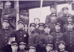 赴任してきたヴォーリズ（中央の無帽の人）と制服制帽の学生たちの集合写真