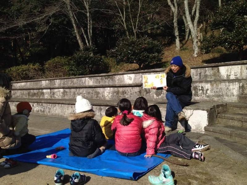 公園で子どもたちに読み聞かせをしている様子の写真