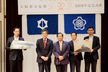 富士宮市・近江八幡市夫婦都市提携50周年記念式典にて、それぞれの市の市長が並び記念品の交換をしている写真