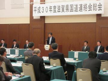 平成30年度滋賀県国道連絡会総会にて、着席する参加者の前で話す市長の写真