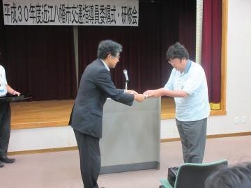 交通指導員委嘱式にて、委嘱を行う市長と、お辞儀をする指導員の写真