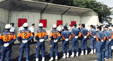 青とオレンジの服を着た県消防操法訓練大会の出場チームへの激励を行う市長の写真