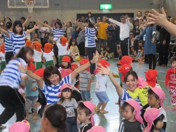 武佐小学校体育館にて行われた武佐子ども園 運動会にて、たくさんの園児やスタッフと一緒に両手を上げて踊る市長の写真