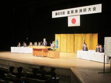 第63回滋賀県消防大会の壇上にて、着席する参加者の前で話す市長の写真