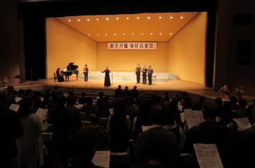 第36回近江八幡市民音楽祭にて、壇上でのピアノ演奏や歌とともに、楽譜を手に客席で歌う参加者らの写真