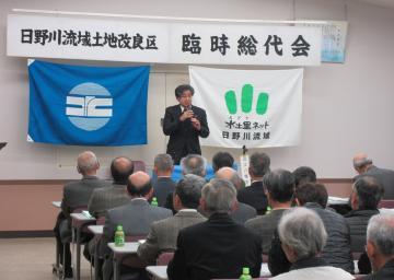 日野川流域土地改良区臨時総代会にて、着席する参加者の前で話す市長の写真