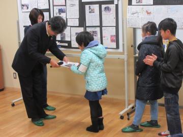 市長が小学生の女の子にSDGs子ども特派員任命書を手渡す市長の写真