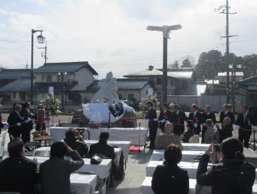 常楽寺相撲モニュメント除幕式・入魂式にて、モニュメントの両脇でロープを握る男性らと、着席して見守る参加者の写真