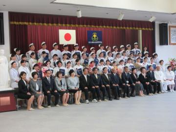 近江八幡市立看護専門学校卒業証書授与式にて、看護服を着た卒業生やスーツの教職員と市長の集合写真