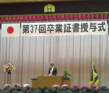 八幡東中学校卒業証書授与式にて、壇上でマイクを手に話す市長の写真
