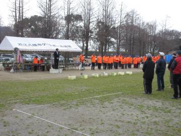第31回読売旗親善ゲートボール大会にて、オレンジのジャージを着て並ぶ人たちの横の壇上で、参加者を前にあいさつをする市長の写真