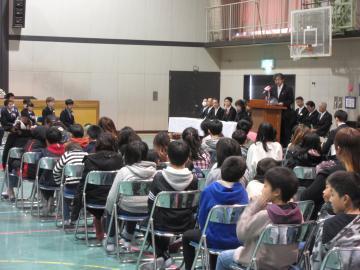 武佐小学校卒業証書授与式にて着席した卒業生を前に壇上のマイクで話す市長の写真