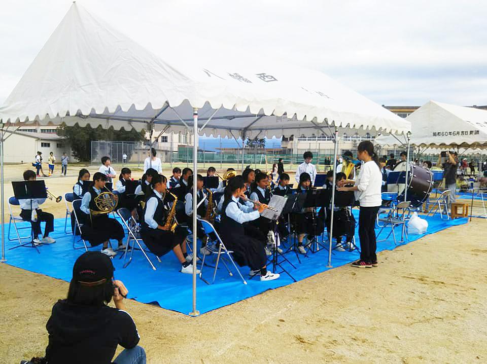 桐原学区市民運動会：白テントの下で吹奏楽を演奏している制服を着た男女の写真