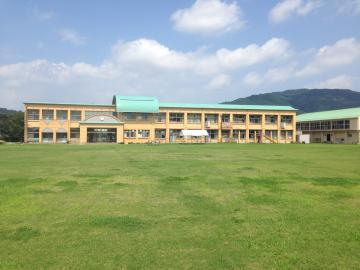 老蘇小学校の芝生の校庭から校舎を望む写真