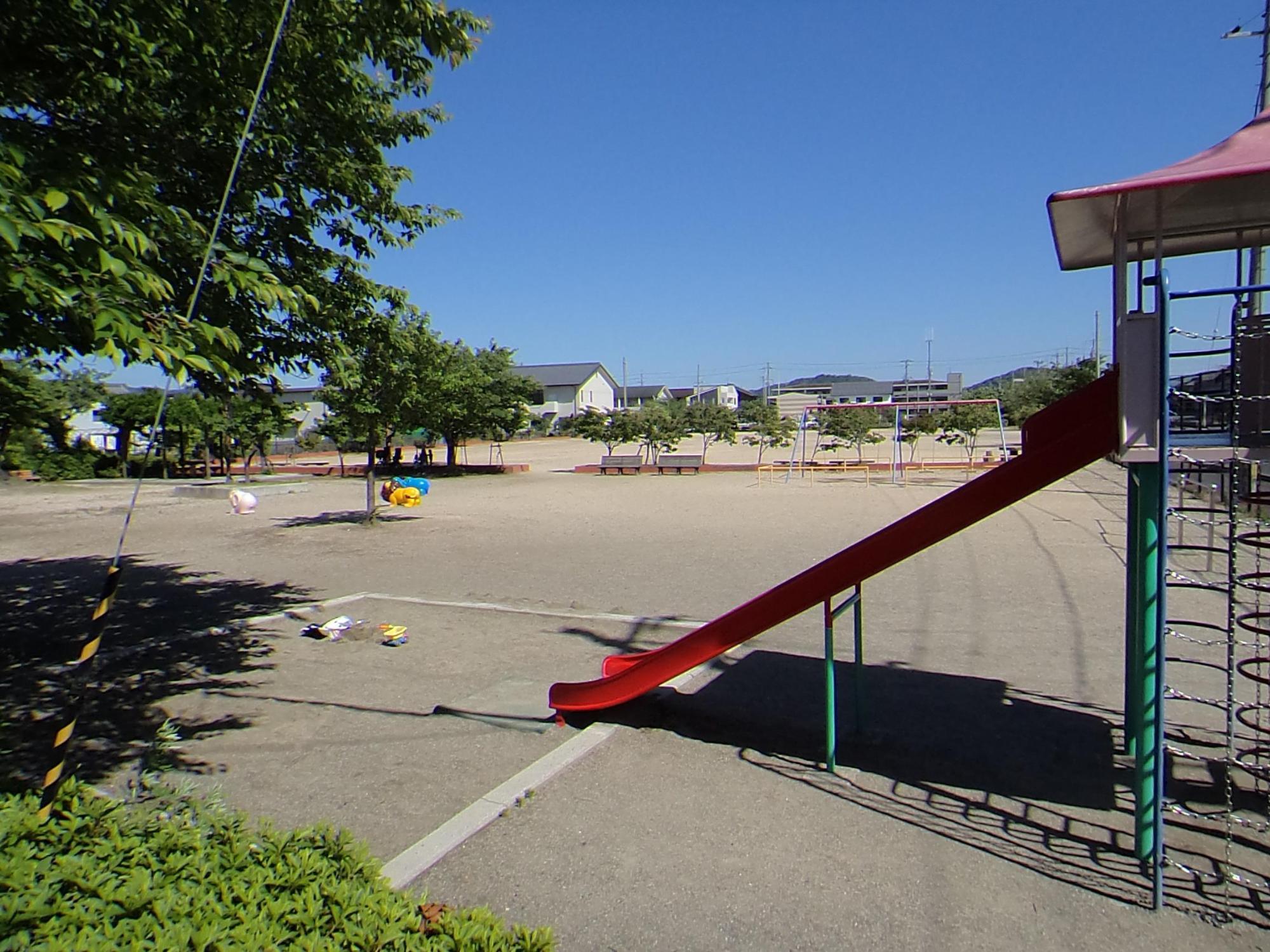 大きなすべり台と奥に動物をかたどった遊具のある駅南第3児童公園の写真